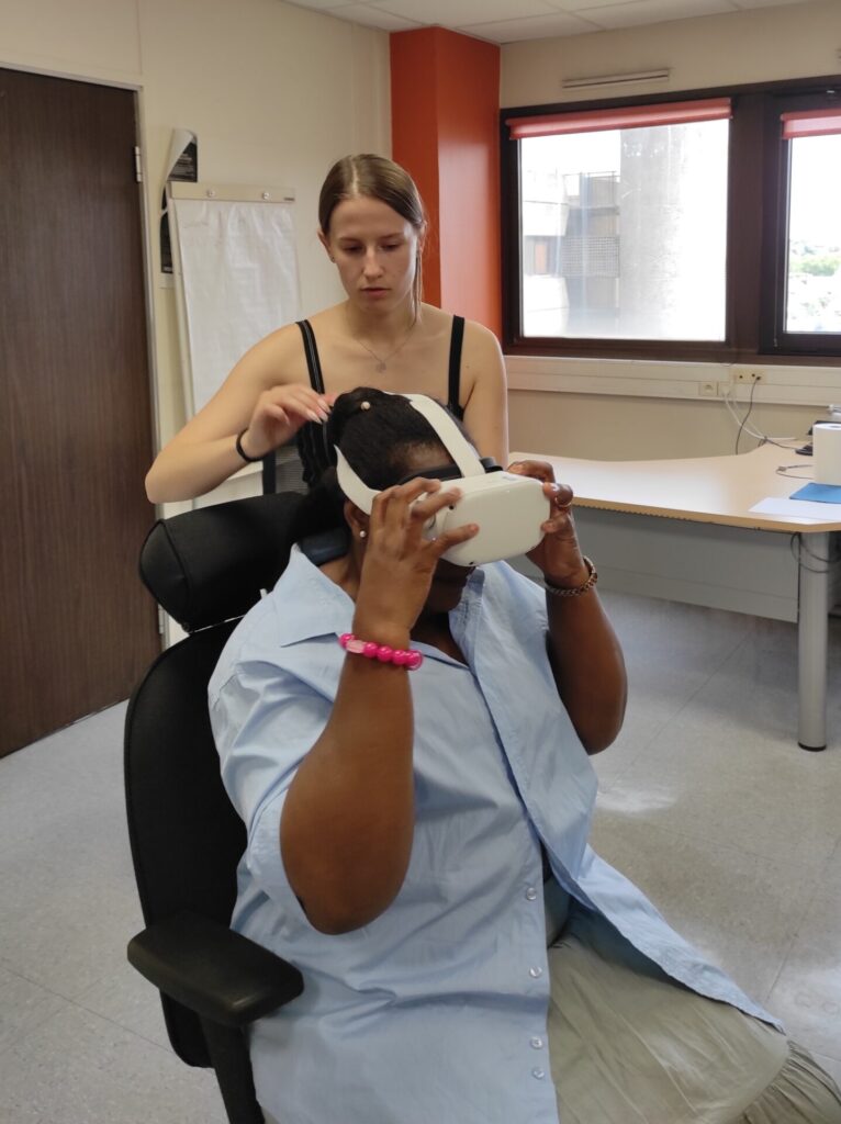 Une personne teste un casque de réalité virtuelle, accompagnée par une professionnelle lors d’un atelier