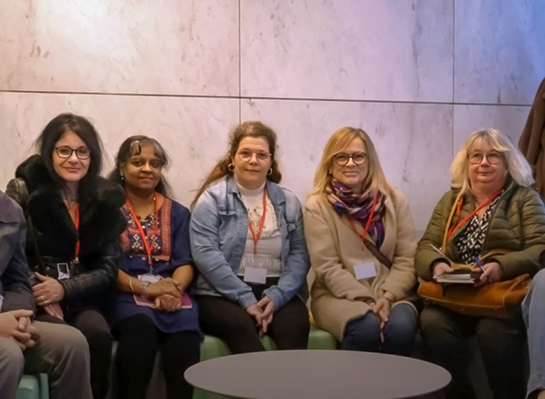 Cinq participantes assises côte à côte posent pour une photo de groupe